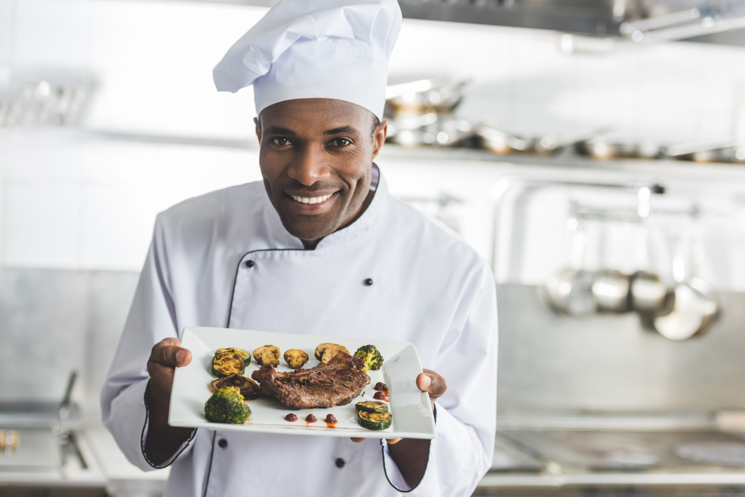 happy,african,american,chef,holding,plate,with,cooked,steak,and